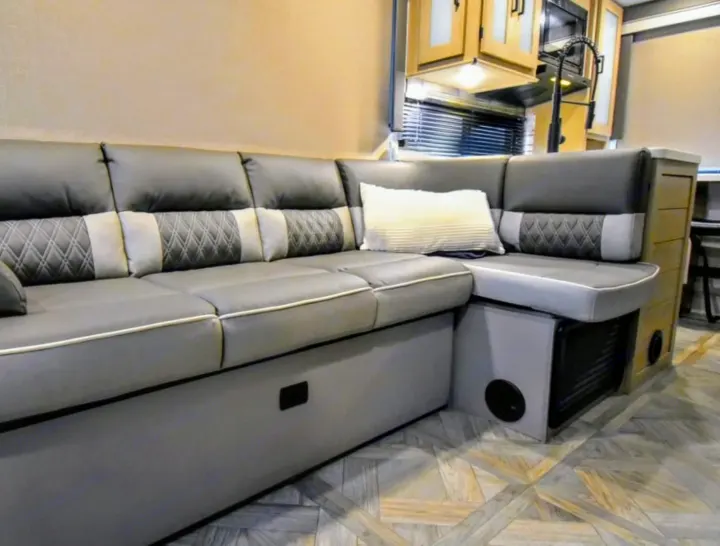 Modern gray L-shaped sofa and compact kitchen in this RV rental. Comfort and style await your next road trip adventure.. Forest River Salem Cruise Lite 2024