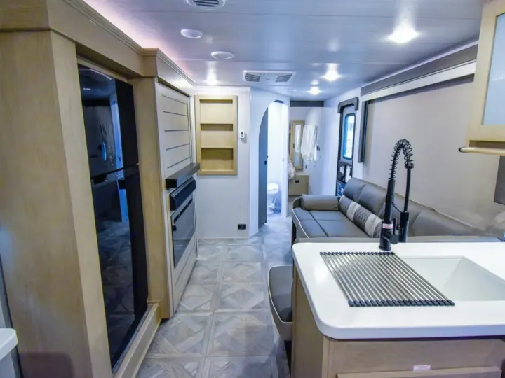 RV rental: Bright, modern interior shows a kitchen (sink, fridge, oven), adjacent sofa living area, & rear bathroom access.. Forest River Salem Cruise Lite 2024