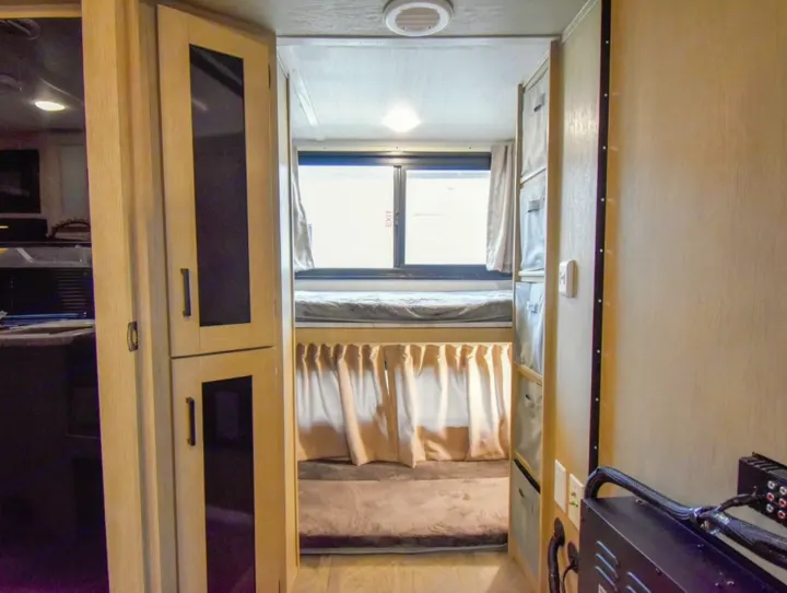 RV rental interior: cozy bunk beds with curtains, storage cabinets, and compact layout, ideal for families on the go.. Forest River Salem Cruise Lite 2024