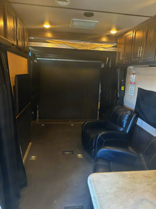 Inside an RV rental toy hauler, featuring a spacious cargo area, recliners, fold-up seating, and a bunk bed.. Forest River Nitro Xlr 2017
