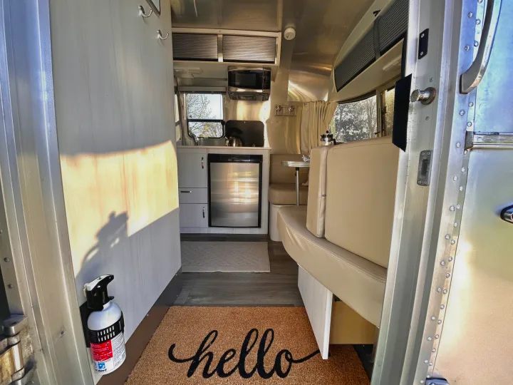 Cozy Airstream RV rental interior with kitchen, dining, and "hello" mat. Bright and modern.. Airstream Sport 2018