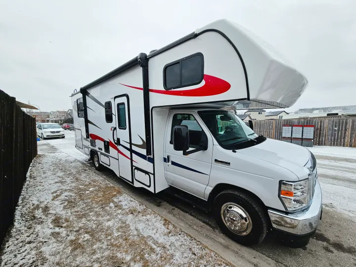 This white Class C RV rental with red and black graphics is ready for winter adventure, parked on a snowy street.. Forester 2651 CDW 2022