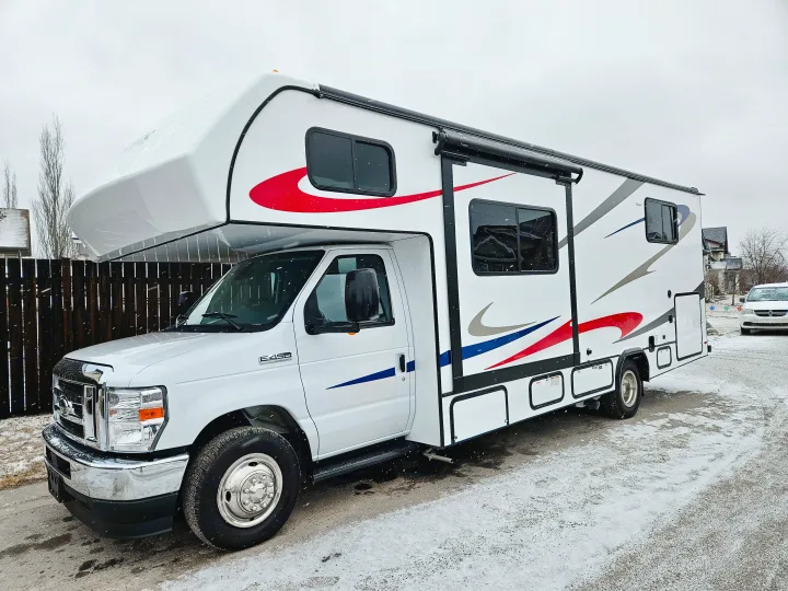 White Class C RV rental with bold red, blue, and gray graphics, parked on a snowy street, ready for adventure.. Forester 2651 CDW 2022
