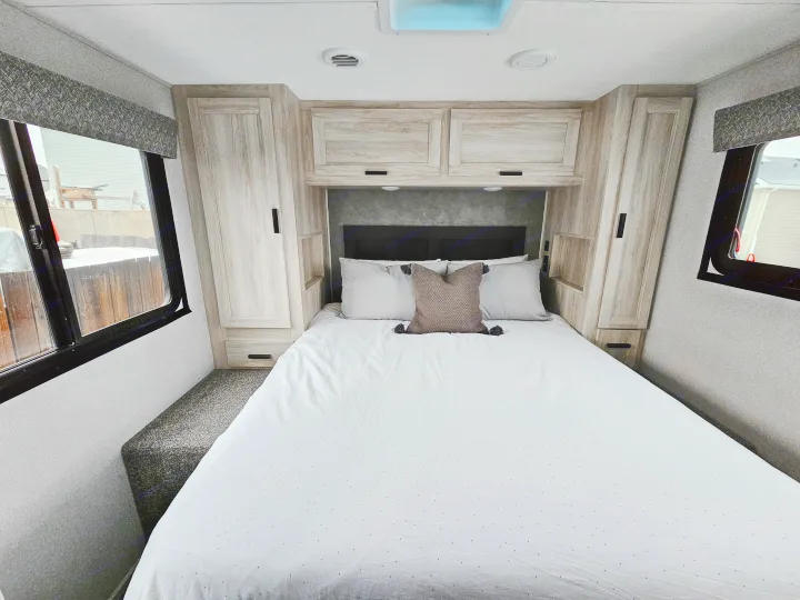 Comfortable RV rental bedroom with light-colored cabinetry, a cozy bed, and windows on either side.. Forester 2651 CDW 2022