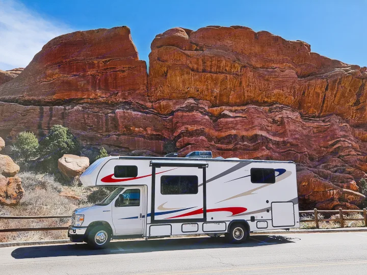 This white rv rental is parked on a road beside majestic red rock formations under a clear blue sky.. Forester 2651 CDW 2022