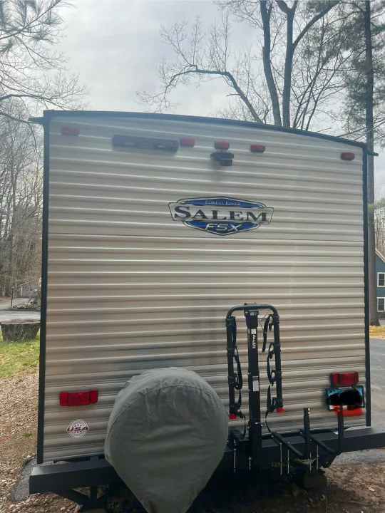Rear view of a Forest River Salem FSX travel trailer (RV) with bike rack and spare tire, ideal for an rv rental adventure.. Forest River Salem 2024