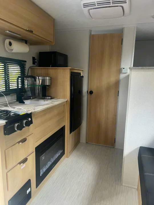 Inside this modern RV rental, discover a practical kitchen with sink, stovetop, microwave, coffee maker, and fireplace.. Forest River Salem 2024