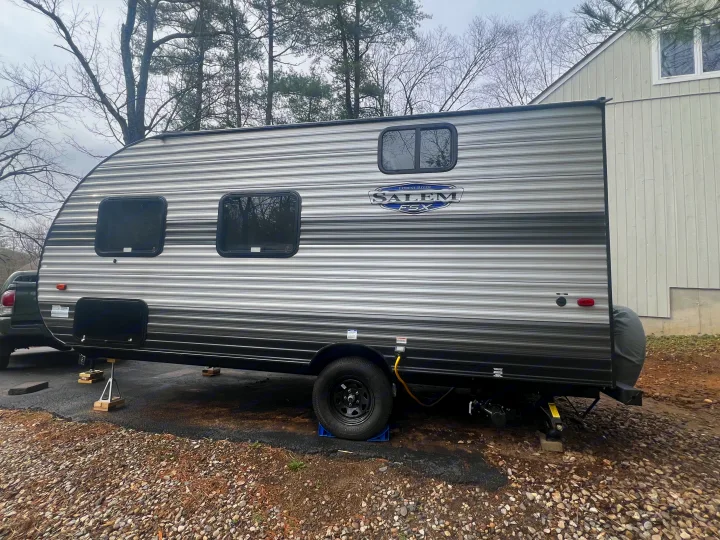 Grey and black striped Salem FSX travel trailer, a great option for an rv rental. It's parked outside with trees and a house.. Forest River Salem 2024