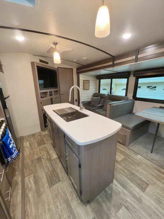 Inviting RV rental interior: kitchen island, entertainment center, and cozy living/dining area with recliners and dinette.. Crossroads RV Sunset Trail Super Lite 2021