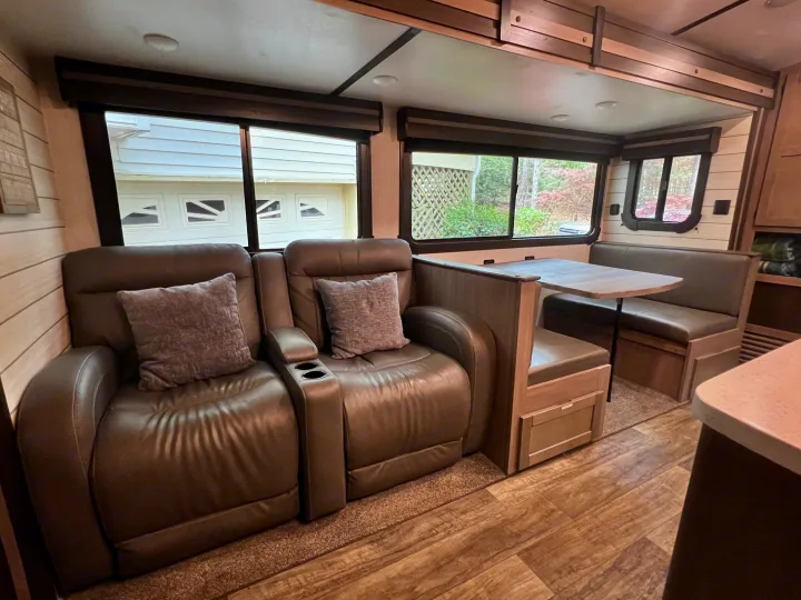 Relax in this RV rental's cozy living space! Featuring plush recliners, a dining booth, and scenic windows.. Crossroads RV Sunset Trail Super Lite 2021