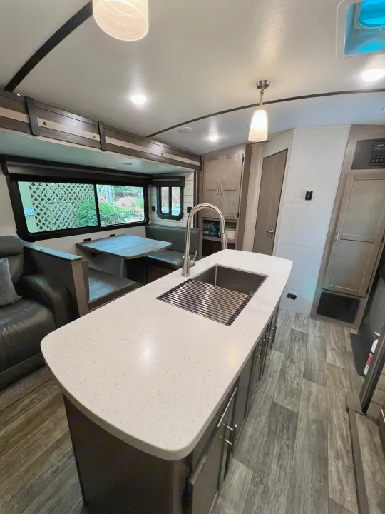 Explore this RV rental's inviting interior: sleek kitchen island, dining area, and comfy lounge.. Crossroads RV Sunset Trail Super Lite 2021