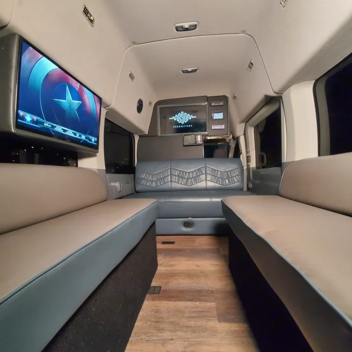 Spacious RV rental interior with comfortable seating, a large entertainment screen showing Captain America, and modern controls.. Ford Custom Transit 2017