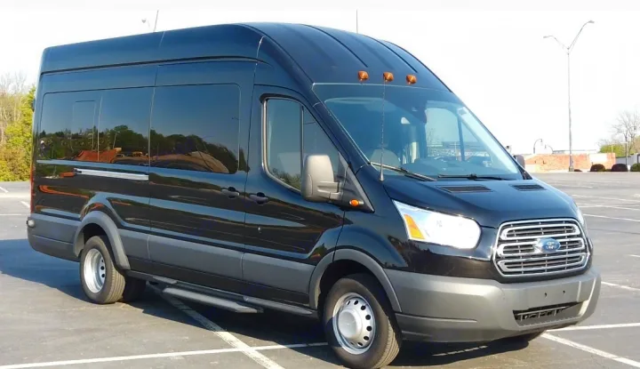 Spacious black Ford Transit high-roof van for RV rental. Features tinted windows & running boards, parked in a lot.. Ford Custom Transit 2017
