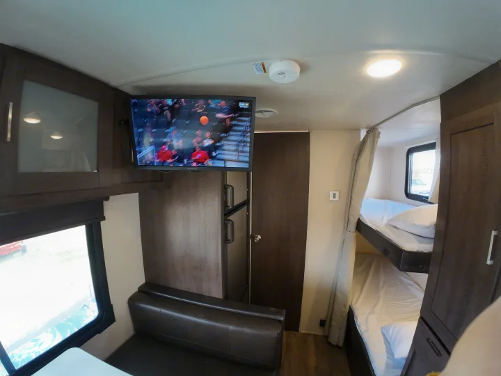 This RV rental interior offers a TV, comfy bunk beds, and dinette, creating a functional and cozy living space.. Forest River Salem Cruise Lite 2018