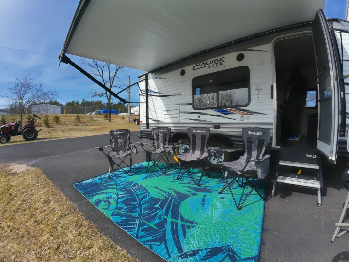 An inviting RV rental scene with an extended awning, comfy Nazhura camping chairs, and a tropical outdoor mat ready for relaxation.. Forest River Salem Cruise Lite 2018