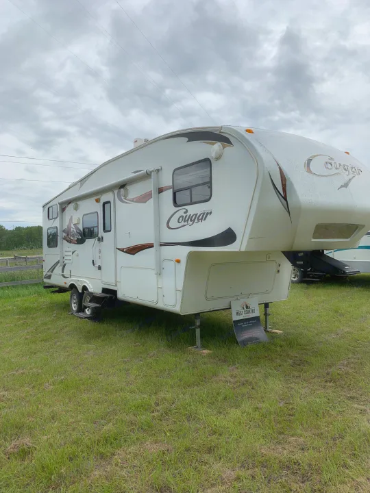 A white Cougar Keystone fifth-wheel RV rental (holiday trailer) on a grassy field under cloudy skies.. Keystone Cougar 280BHS 2015