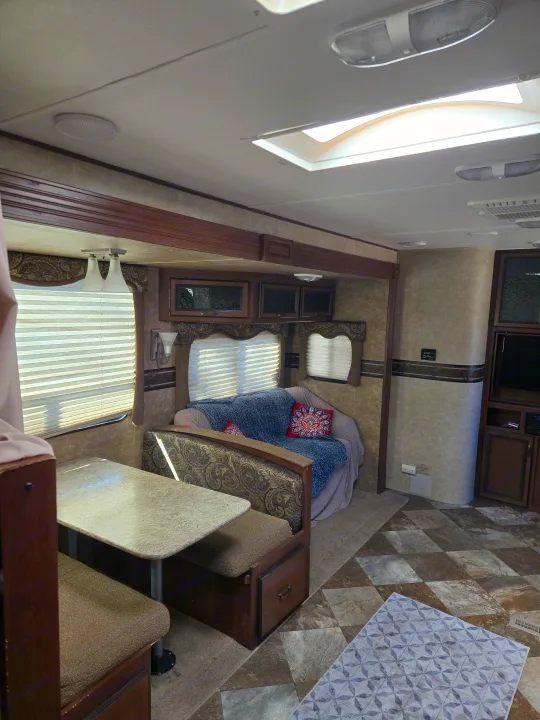 RV rental interior showcasing a comfortable dinette, sofa with decorative pillows, and overhead storage, ready for travel.. Crossroads RV Zinger 2014