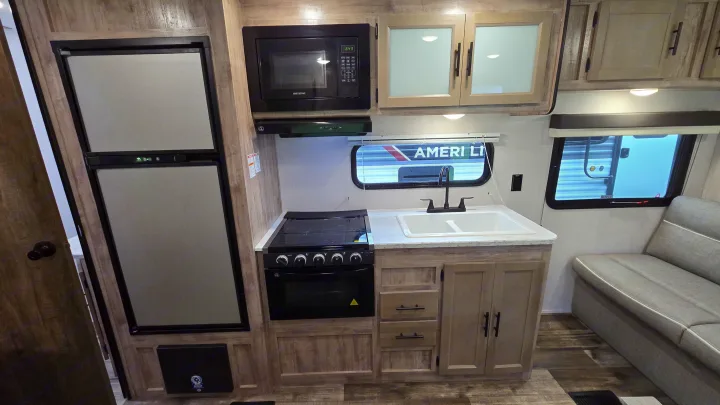 RV rental: Modern travel trailer kitchen with fridge, microwave, stove, sink, and seating. Ideal for comfortable road trips.. Gulf Stream Trailmaster 2024