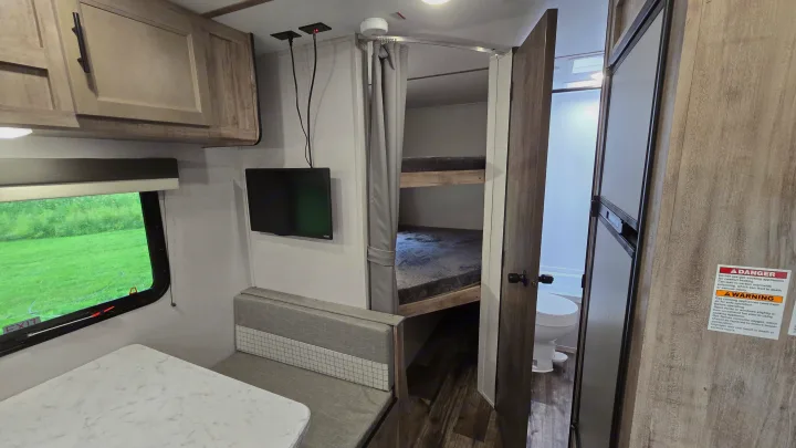 Explore this RV rental's inviting interior, showcasing a dinette, bunk beds, and a convenient bathroom, perfect for family adventures.. Gulf Stream Trailmaster 2024