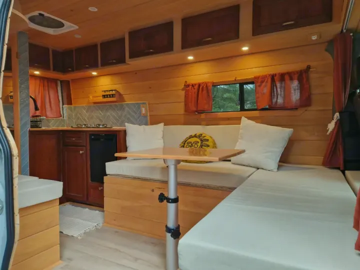 Explore this cozy RV rental's wooden interior: a kitchenette, dining area with adjustable table, and comfy seating/bed.. Dodge Sprinter Van 2008