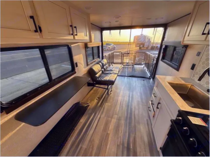 Inside a modern RV rental: open floor plan with kitchen, sofa, and a spacious rear garage/patio area.. Open Range Open Range 2024