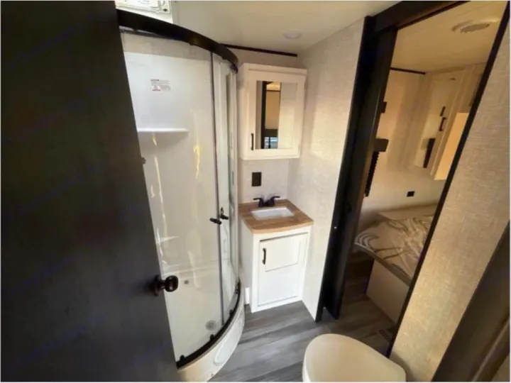 RV rental bathroom with a compact shower, vanity, toilet, and sliding door to the bedroom.. Open Range Open Range 2024