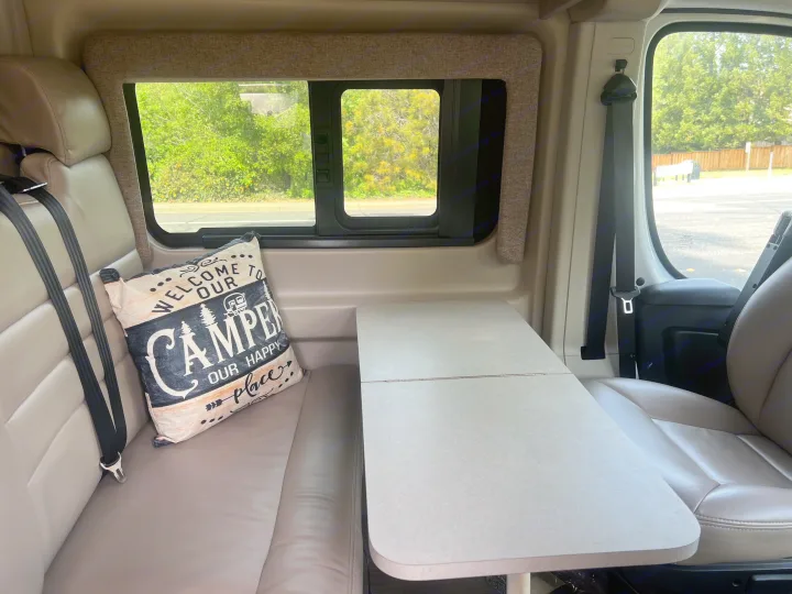 Inside an RV rental: a cozy dinette with bench seating, a "CAMPER" pillow, and a versatile table.. Thor Motor Coach Sequence 2022
