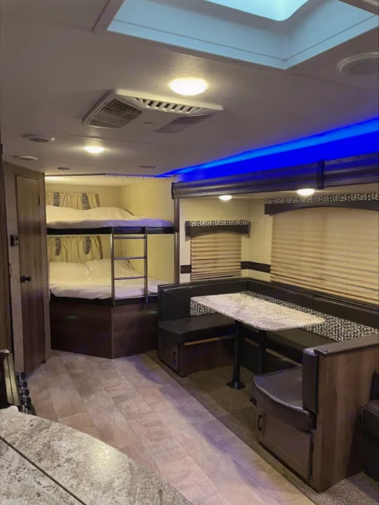 Inside this RV rental: bunk beds, a comfy dinette with table, and blue accent lighting. Perfect for family adventures.. KZ Connect 2018