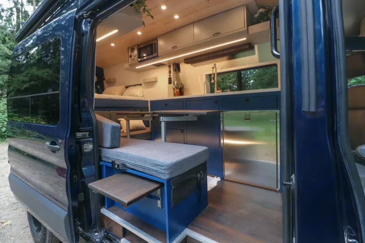 Explore this modern RV rental! Spacious camper van interior with full kitchen, dining area, and cozy bed for your adventures.. Ford Transit 2016