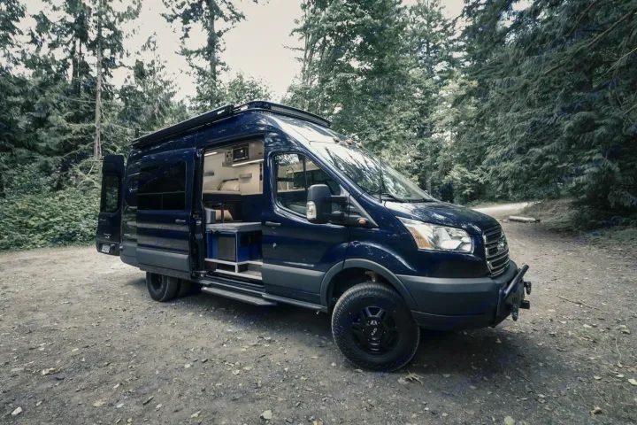 Explore nature with this dark blue custom off-road rv rental camper van, revealing its cozy interior.. Ford Transit 2016