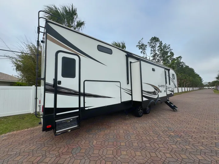 This large white fifth-wheel RV, with its modern graphics & extended steps, is ideal for your next rv rental adventure.. Forest River Sabre 2021