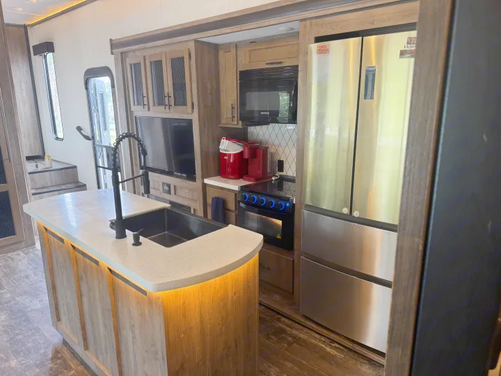 Spacious, modern RV rental interior featuring an illuminated kitchen island, full appliances, and living area.. Forest River Sabre 2021