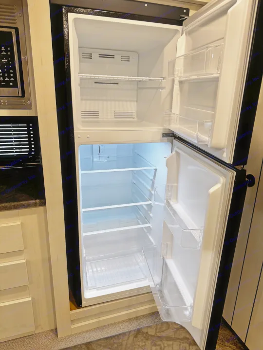 Empty, clean two-door refrigerator with freezer in an RV rental kitchen, ready for use.. Forest River Puma 2026