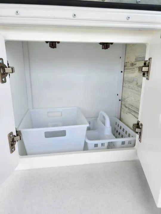 Inside an RV rental: A clean, open white cabinet revealing two plastic organizers on a speckled counter.. Modern Buggy Lil Buggy 10RK 2025