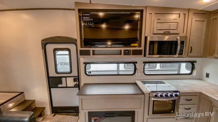 RV rental interior with a fully equipped kitchen, entertainment TV area, cabinetry, and main entry door.. Forest River Coachmen Chaparral Lite 2022