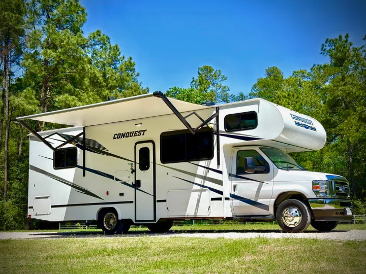 Ready for adventure! This white Conquest Class C RV rental, with its awning extended, offers comfort for your next outdoor trip.. Gulf Stream Conquest 2025