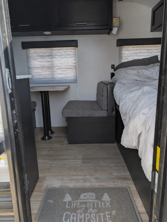 Cozy RV rental interior with dinette, bed, and cabinets, offering a glimpse into compact camper living.. Forest River Cherokee Wolf Pup 2022