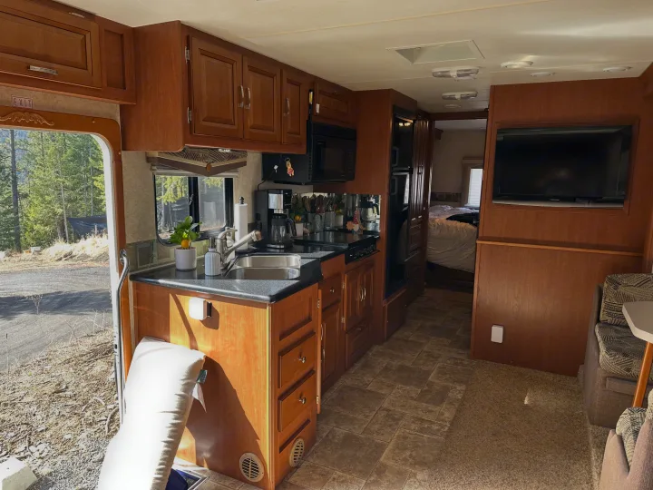 Spacious RV rental interior with a fully equipped kitchen, living area with TV, and a view into the bedroom.. Forest River Georgetown 2011