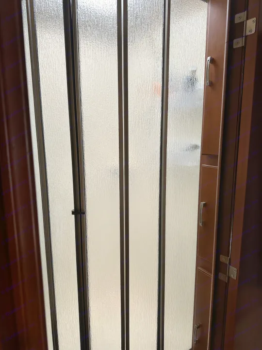 Inside an RV rental: a textured frosted glass privacy partition next to a compact wooden cabinet. Ideal for bathroom separation.. Forest River Georgetown 2011
