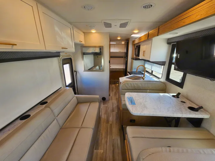 Spacious rv rental interior: sofa, dinette, kitchen, and light wood-look flooring. Modern design.. Thor Motor Coach Four Winds 2026