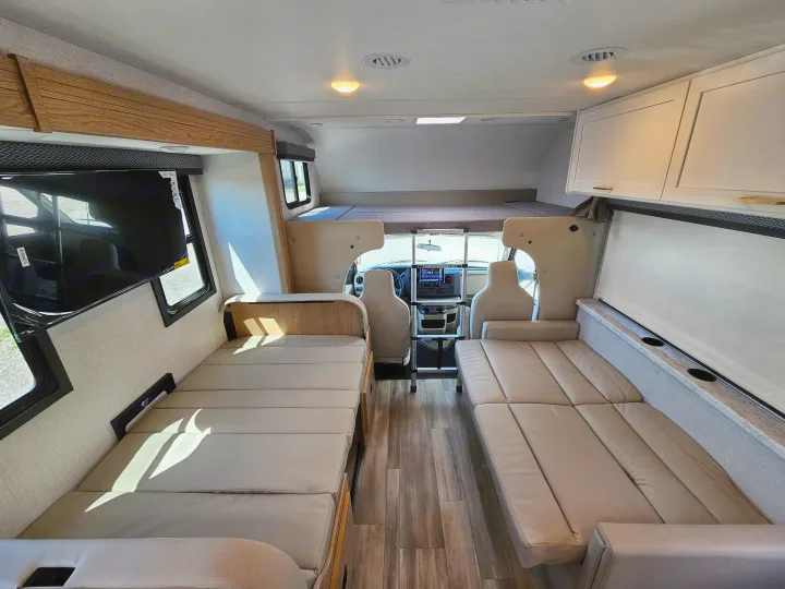 Spacious RV rental interior: View of modern living space with multiple sleeping areas, including an over-cab bunk and convertible sofas.. Thor Motor Coach Four Winds 2026