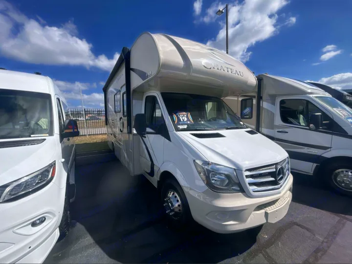 A white Chateau Class C RV on a Mercedes-Benz chassis, with other RVs, parked under a blue sky, suitable for rv rental.. Thor Chateau Sprinter 2018