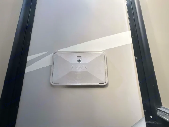 RV rental exterior: a light gray, rectangular outdoor shower port with 'SHOWER' text and a key lock.. Thor Chateau Sprinter 2018