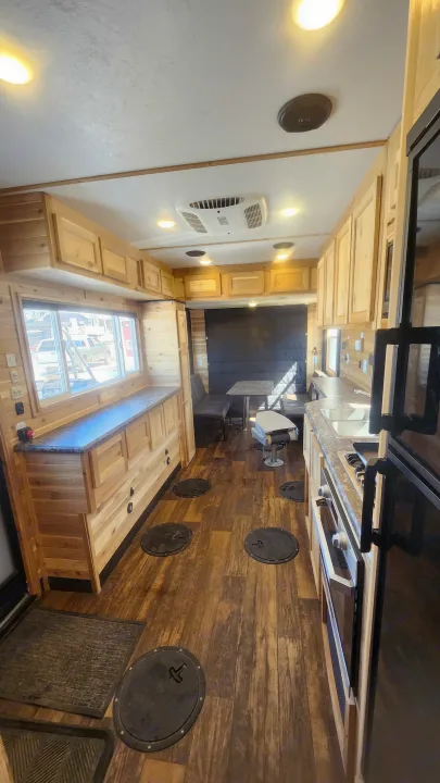 Spacious RV rental interior, an ice fishing house featuring warm wood, a full kitchen, dining area, and several floor fishing holes.. Ice Castle Fish Houses Toy Hauler 2022