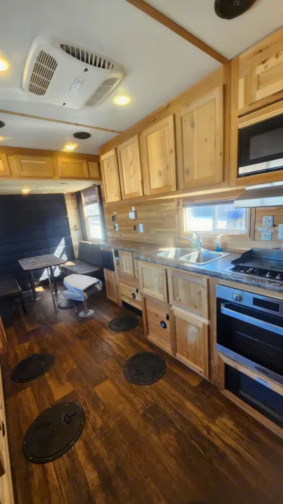 This rv rental boasts a cozy, wood-paneled interior with full kitchen, dining, and unique ice fishing holes.. Ice Castle Fish Houses Toy Hauler 2022