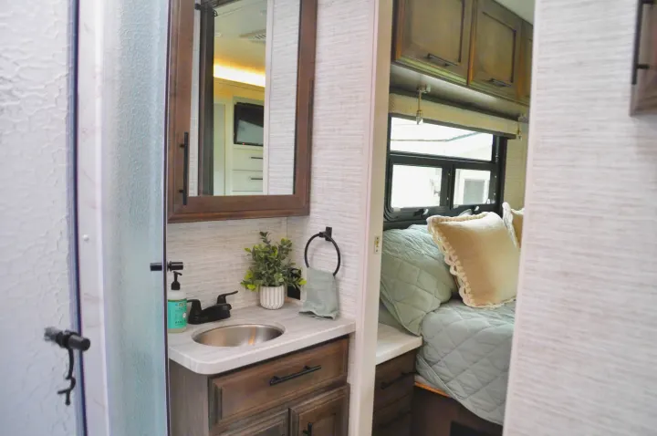 Comfortable RV rental interior: modern bathroom vanity leads to a cozy bedroom area.. Jayco Greyhawk 31F Bunkhouse 2025