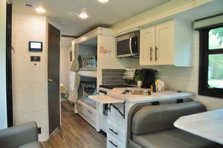Modern RV rental interior with kitchen, bunk beds, and dinette area for comfortable travel adventures.. Jayco Greyhawk 31F Bunkhouse 2025