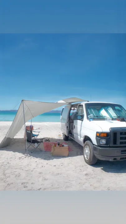 Enjoy the perfect beach escape with an RV rental! This white van with an awning offers shade on a sandy beach by the clear blue ocean.. Ford Econoline 150 2011