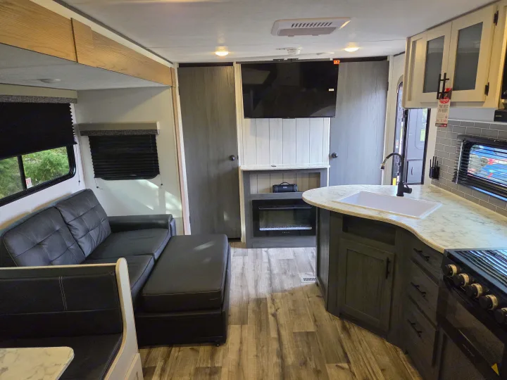 Spacious RV rental interior with kitchen, living area, sofa, dinette, and fireplace. Perfect for your next adventure!. Dutchmen Aspen Trail 2025