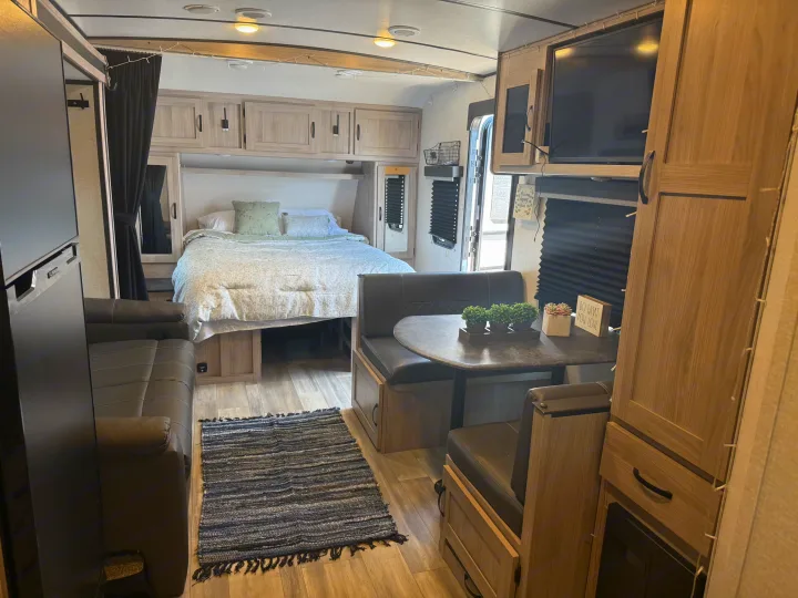 Bright rv rental interior showcases a cozy bed, comfortable dinette, sofa, and TV, with light wood finishes.. Forest River Coachmen Northern Spirit Ultra Lite 2023